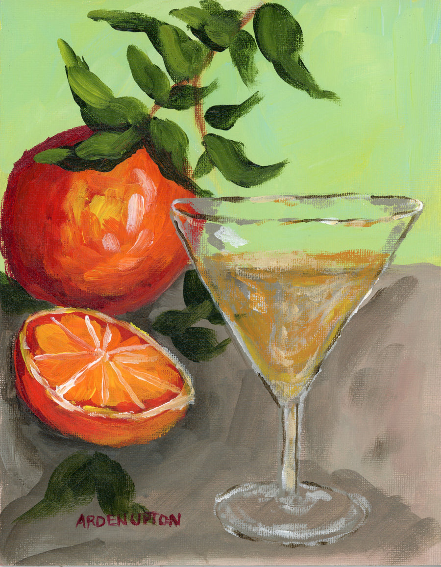 A Close up of Southern Artist Arden Upton's Orange Thing Original Painting from the Frank's Table Collection where you can see the details in her brush strokes and use of colors. The painting shows an orange with a stem and leaves, a half of an orange in front of it and an orange martini sitting on a grey table in front of a green background. This piece pairs well with the Orange No Thing Piece and lobster painting, as well as all of the other pieces in this collection. 