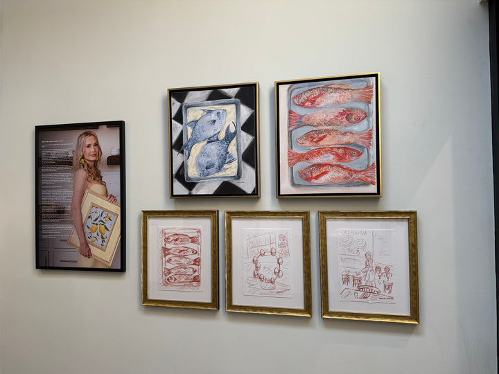 Gallery wall of Arden Upton's Frank's Table Collection featuring five of her paintings and sketches and a photo of her with her biography. The Oil Paintings are of two blue fish on a platter on a black and white table and of five red fish on. pan on a white background. The three sketches are of five red fish, eggs on an egg stand on a table, and people sitting at a table with  server and tables with place settings. Perfect for Gathering spaces, gallery walls and kitchens