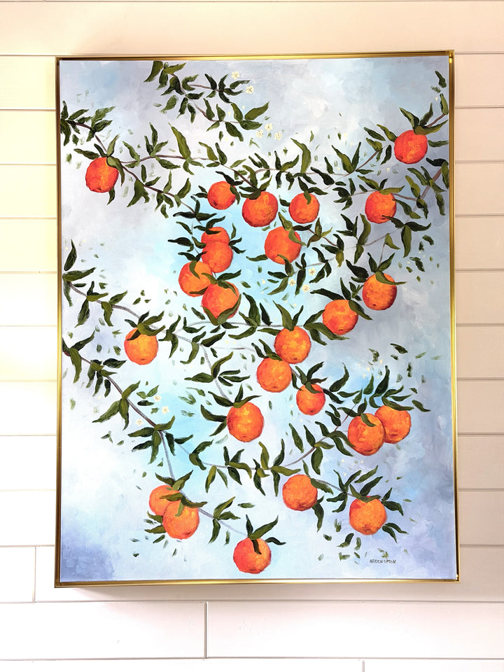 Original oil painting by Southern artist Arden Upton o many branches bursting with ripe oranges and green leaves on a light blue cloudy background. It is hung on a shiplap wall and framed in gold. It would be beautiful in a kitchen or dining room as wlel as many other rooms in a home. 