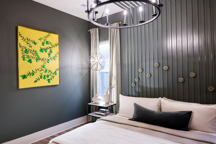 Original Painting by Southern Artist Arden Upton featuring branches of a lime tree full of vibrant green limes and leaves on a bright yellow background hung in a moody bedroom with dark grey walls. Perfect for decorating the walls of dining rooms, kitchens and other areas.