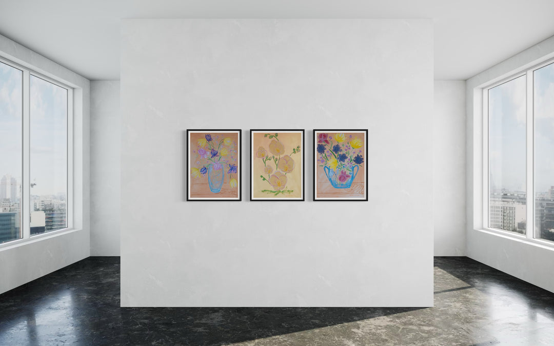 3 framed giclee prints from Arden Upton's Flowers that Last collection styled as a gallery wall in a bright, open space featuring paintings of vibrant, colorful yellow, purple, pink and red flowers with green leaves in vases