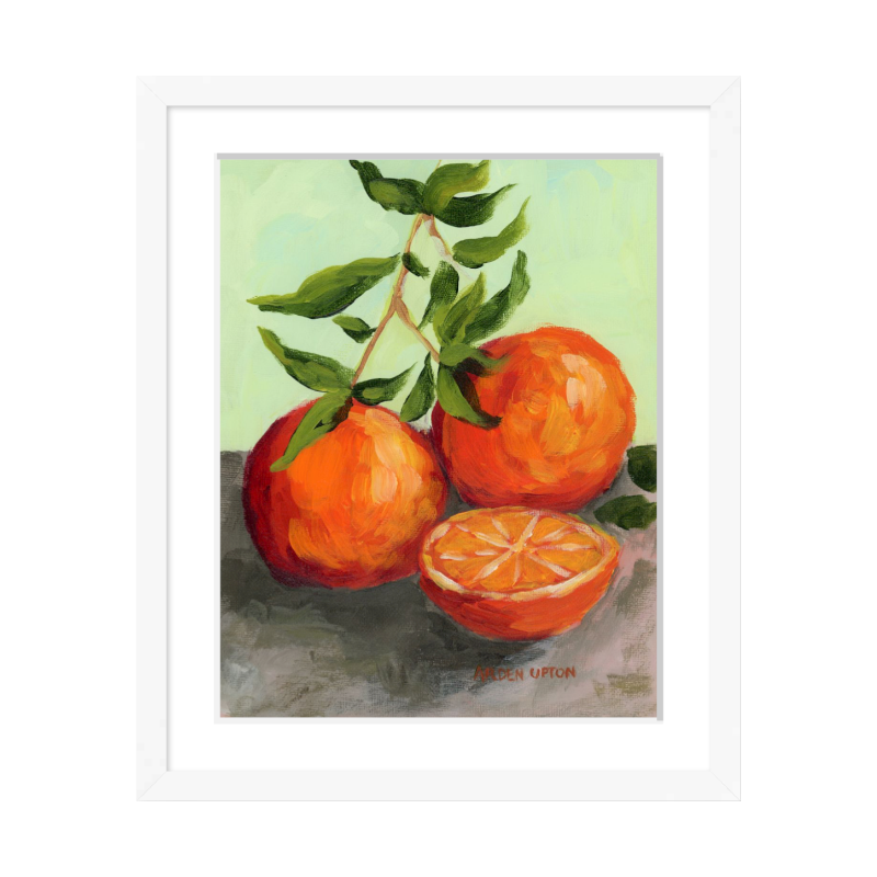 Culinary wall art – Orange Still Life framed painting by Arden Upton, ideal for kitchen and dining room décor. Painting shows teo and a half oranges on a green leaf-covered stem on a grey surface with a lime green background