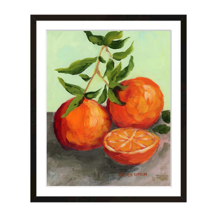 Kitchen gallery wall décor – foodie paintings with life-like oranges in orange, red, and lime green, framed in black or white.