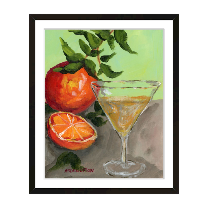 A painting of a yellow Martini and an orange and a half on an orange tree stem sitting. on grey table painted in bold orange, red and green colors, with great texture and detail framed in a black frame. great for for kitchens, pantries, dining rooms, and entertaining spaces