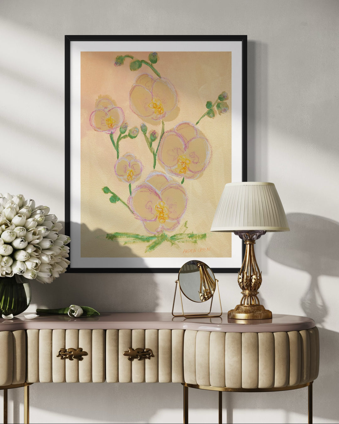 A large framed fine art print featuring a painting of pink orchids with green leaves on a beige and golden background, From Arden Upton's Flowers that Last collection, styled over an envtry way table 
