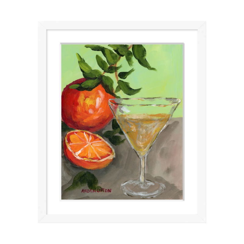 A painting of a yellow Martini and an orange and a half on an orange tree stem sitting. on grey table painted in bold orange, red and green colors, with great texture and detail framed in a white frame. great for for kitchens, pantries, dining rooms, and entertaining spaces