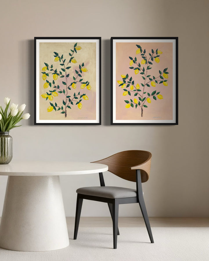 2 museum-quality fine art giclée prints of a lemon tree, featuring vibrant yellow lemons on a lemon tree with green leaves against a pink and yellow background, part of Arden Upton's Lemonade Series and styled side by side over a table