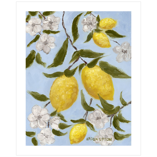 A framed art print featuring a painting from Arden Upton's Lemonade Collection of lemons , leaves and white floral elements against a blue background, with a white mat and black frame.