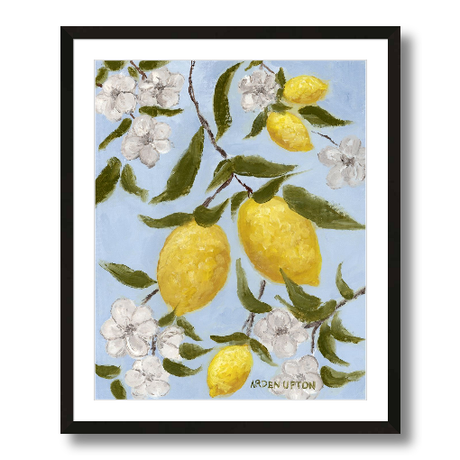 A framed art print featuring a painting from Arden Upton's Lemonade Collection of lemons , leaves and white floral elements against a blue background, with a white mat and black frame.