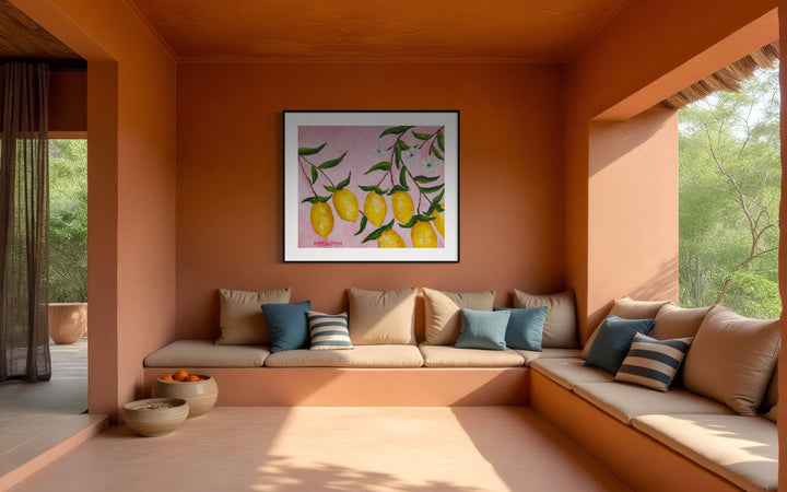 Large scale print of a painting from Arden Upton's Lemonade Series of bright yellow lemons with green leaves and white flowers hanging from a branch on a pink background styled in an outdoor seating area