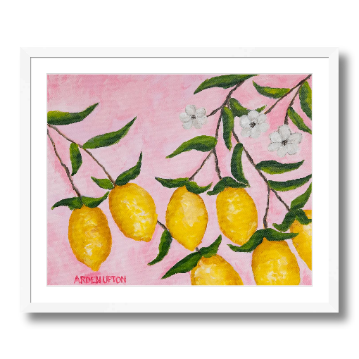A framed art print featuring a painting from Arden Upton's Lemonade Collection of lemons, leaves and white floral elements against a pink background