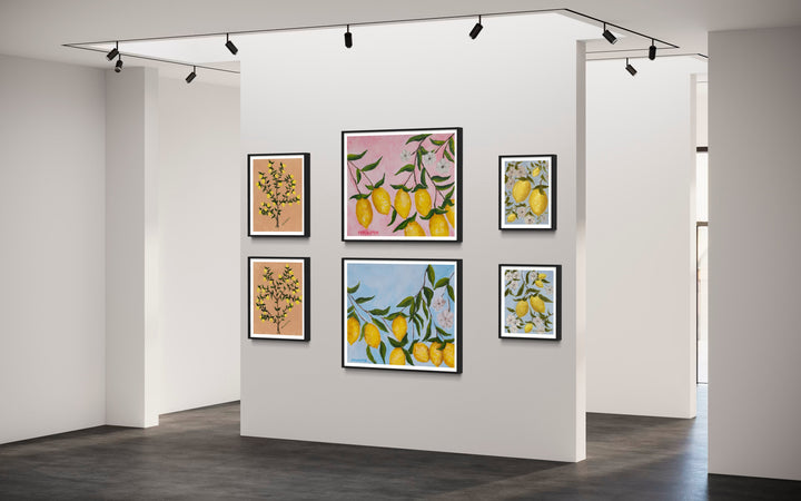 Gallery wall of prints from Arden Upton's Lemonade series featuring her original paintings of lemon trees and lemons hanging on branches with white flowers and pink and blue backgrounds