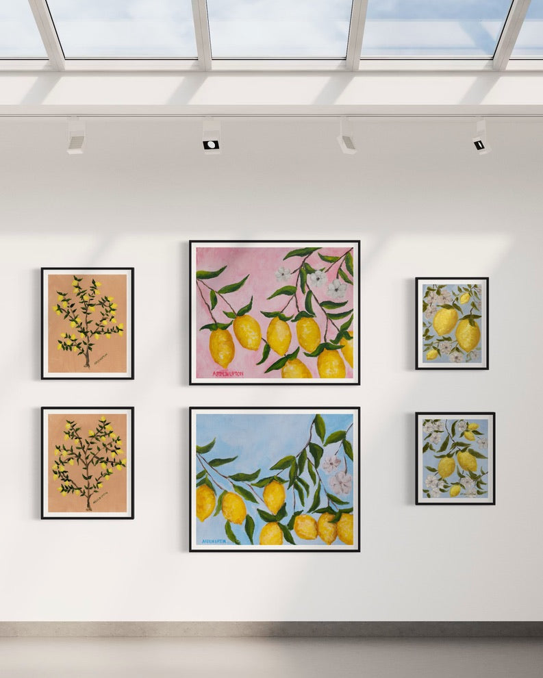 Gallery wall of prints from Arden Upton's Lemonade series featuring her original paintings of lemon trees and lemons hanging on branches with white flowers and pink and blue backgrounds