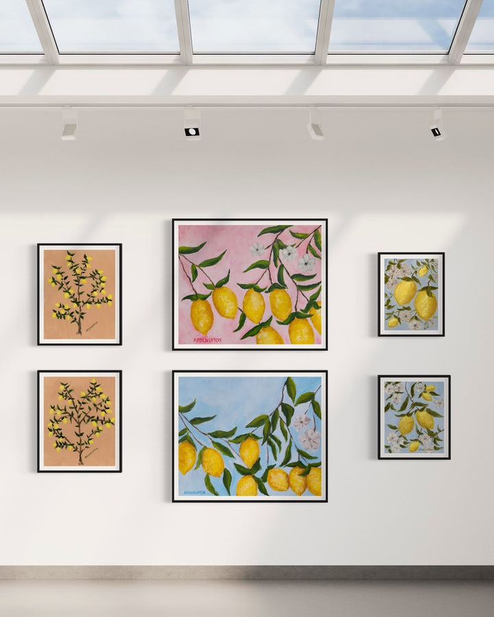 Gallery wall of prints from Arden Upton's Lemonade series featuring her original paintings of lemon trees and lemons hanging on branches with white flowers and pink and blue backgrounds
