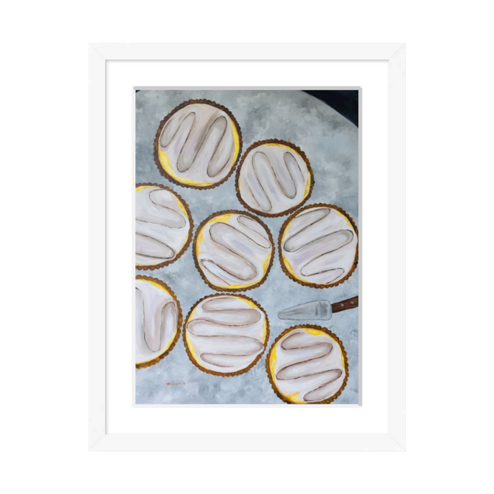 A painting by Southern artist Arden Upton of eight beautifully baked lemon tarts on a table with a tart server. Framed in a white frame