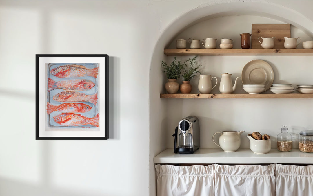 Kitchen interior with shelves displaying various items and  a framed artwork from southern artist Arden Upton on the wall. A beautiful painting of 5 red fish on a silver pan. Vibrant reds, oranges and pinks.